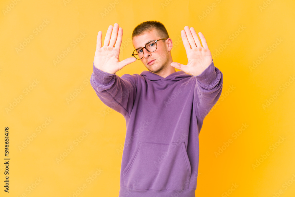 Young caucasian handsome man standing with outstretched hand showing stop sign, preventing you. Young caucasian handsome man standing with outstretched hand showing stop sign, preventing you.