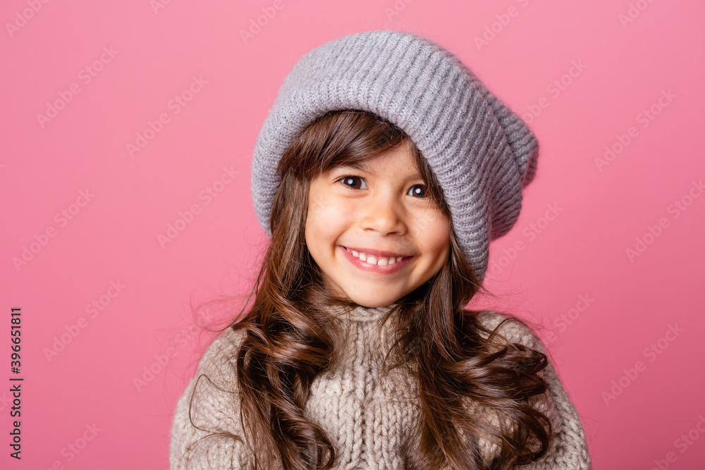 little brunette girl with long hair in winter clothes on a pink background in the Studio. knitwear for children, space for text little brunette girl with long hair in winter clothes on a pink background in the Studio. knitwear for children, space for text