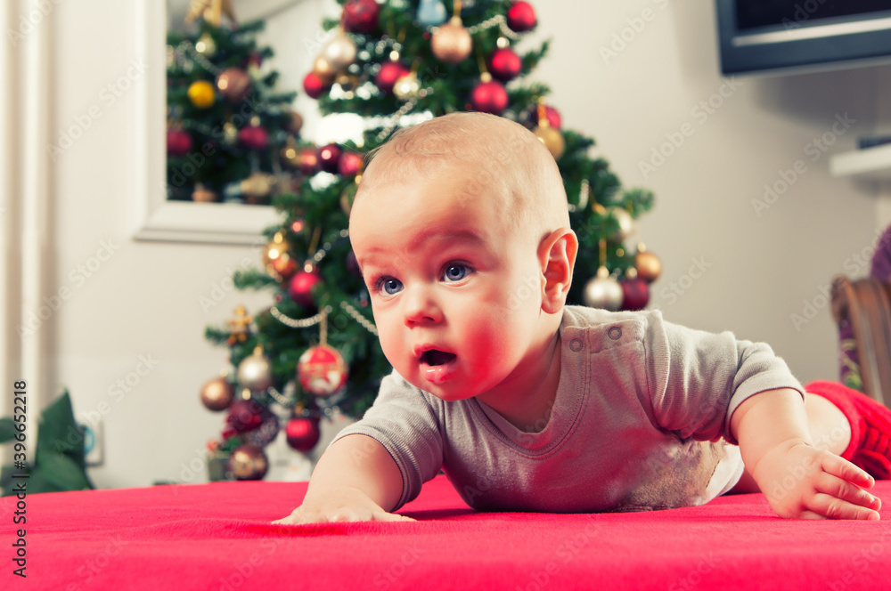 Adorable baby boy crawling beside christmass tree. Concept of celebrations Adorable baby boy crawling beside christmass tree. Concept of celebrations
