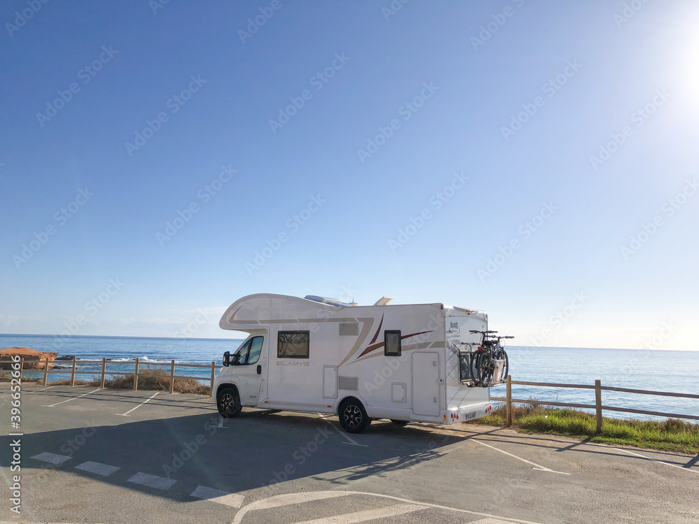 Alicante, Spain - November, 2020: Big family auto house parked next to sea on empty parking with beautiful view to the beach 