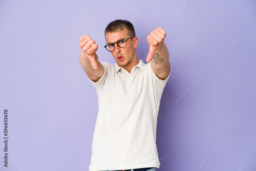 Young caucasian handsome man showing thumb down and expressing dislike. Young caucasian handsome man showing thumb down and expressing dislike.