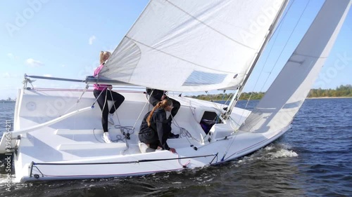 During the regatta, the sailing yacht turns smoothly with the help of a female athlete. Slow motion dynamic shot.