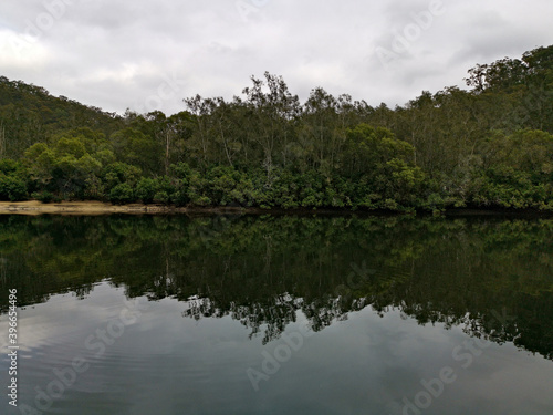 Beautiful view of a creek with reflections of cloudy sky, mountains and trees on water, Crosslands Reserve, Berowra Valley National Park, New South Wales, Australia 