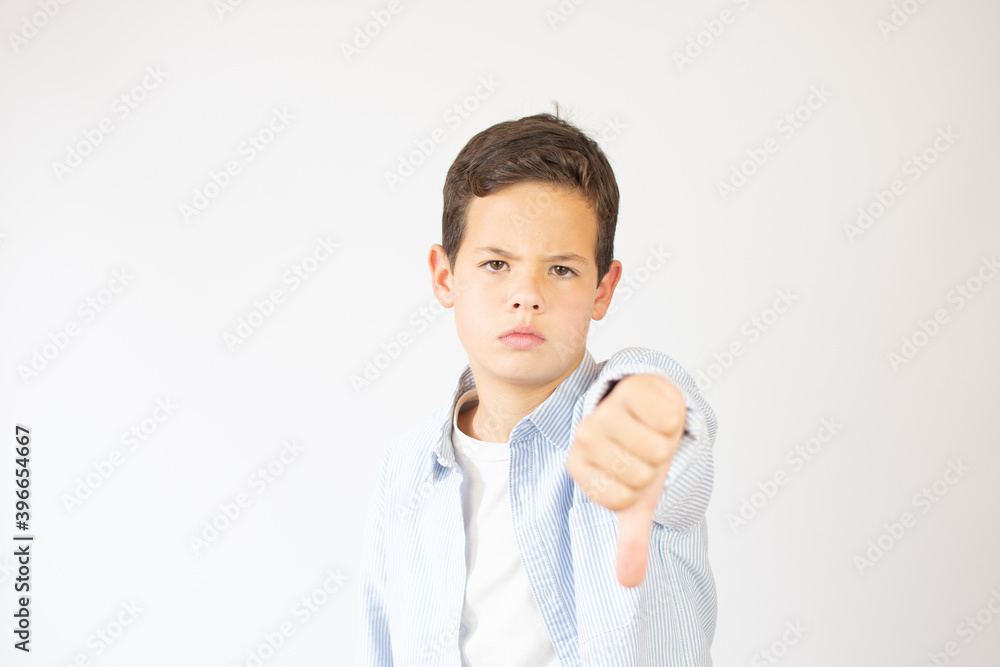 Little boy caucasian kid wearing casual clothes looking unhappy and angry showing rejection and negative with thumbs down gesture. bad expression. Little boy caucasian kid wearing casual clothes looking unhappy and angry showing rejection and negative with thumbs down gesture. bad expression.