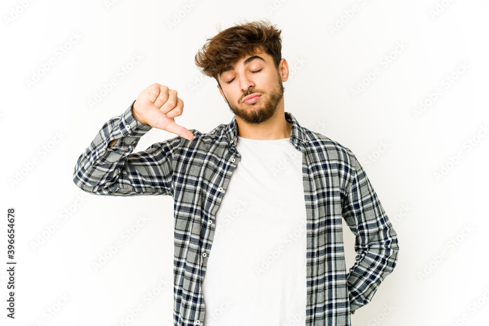 Young arab man on white background showing a dislike gesture, thumbs down. Disagreement concept. Young arab man on white background showing a dislike gesture, thumbs down. Disagreement concept.