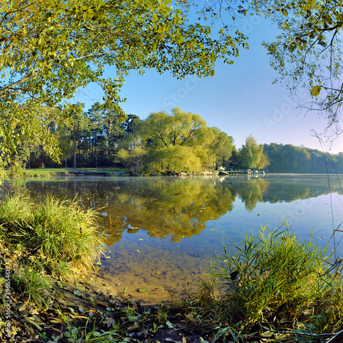 Wide angle landscape with trees reflecting in a lake in autumn