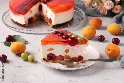 Homemade jelly cake with berries on gray background and slice cake on a plate on foreground. Horizontal format