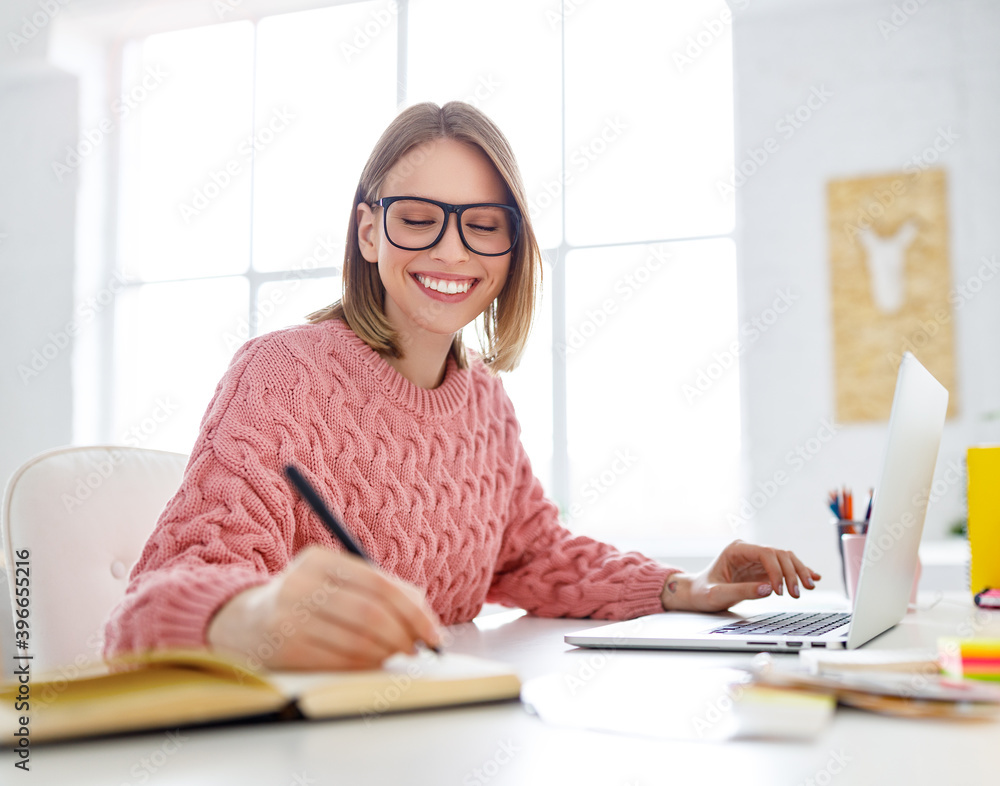 Young freelancer using laptop and making notes. Young freelancer using laptop and making notes.