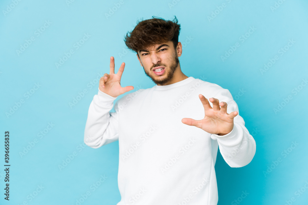 Young arab man on blue background upset screaming with tense hands. Young arab man on blue background upset screaming with tense hands.