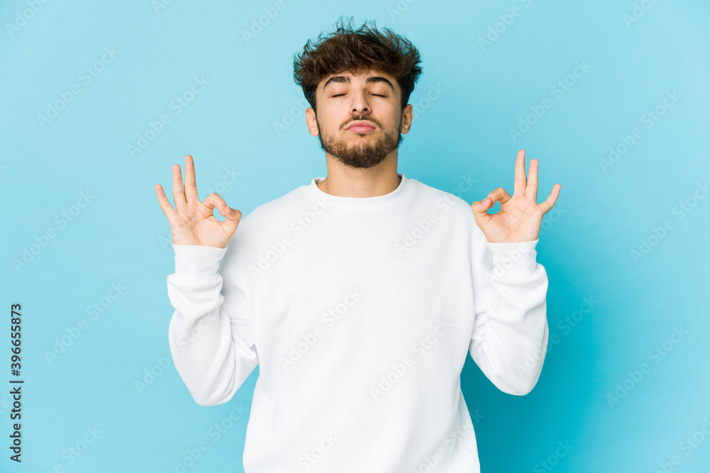 Young arab man on blue background relaxes after hard working day, she is performing yoga. Young arab man on blue background relaxes after hard working day, she is performing yoga.