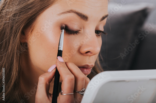 Leinwand Poster Close up portrait of beautiful young woman applying eyeshadow powder