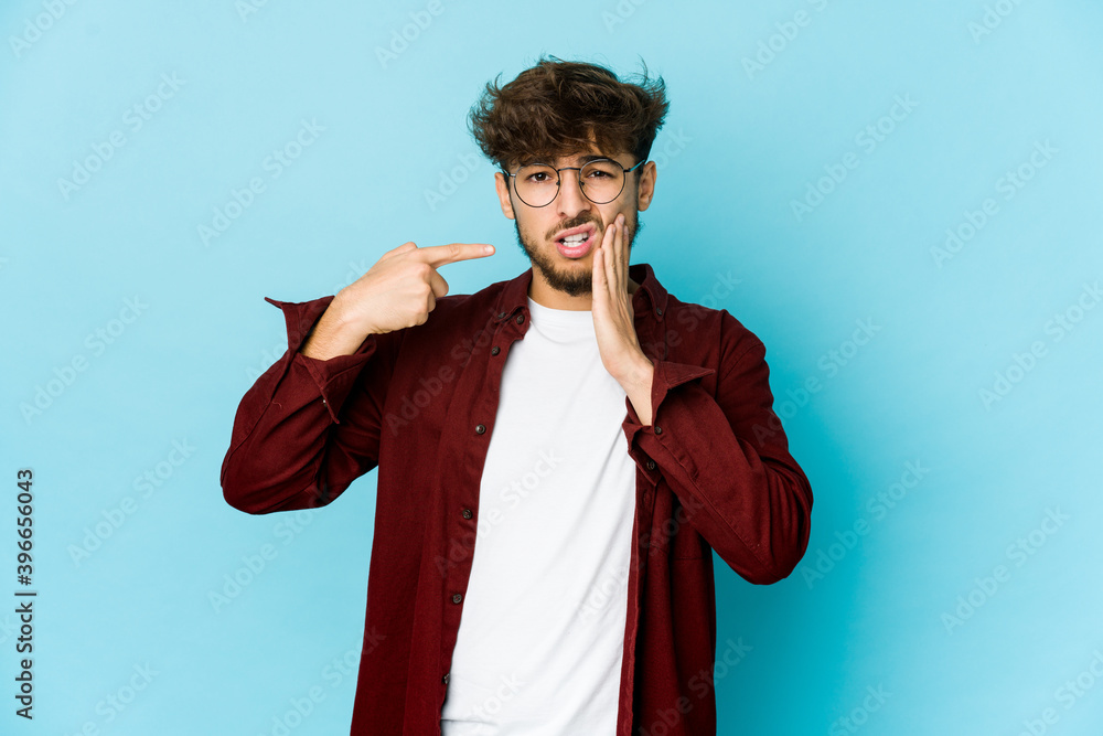 Young arab man on blue background having a strong teeth pain, molar ache.