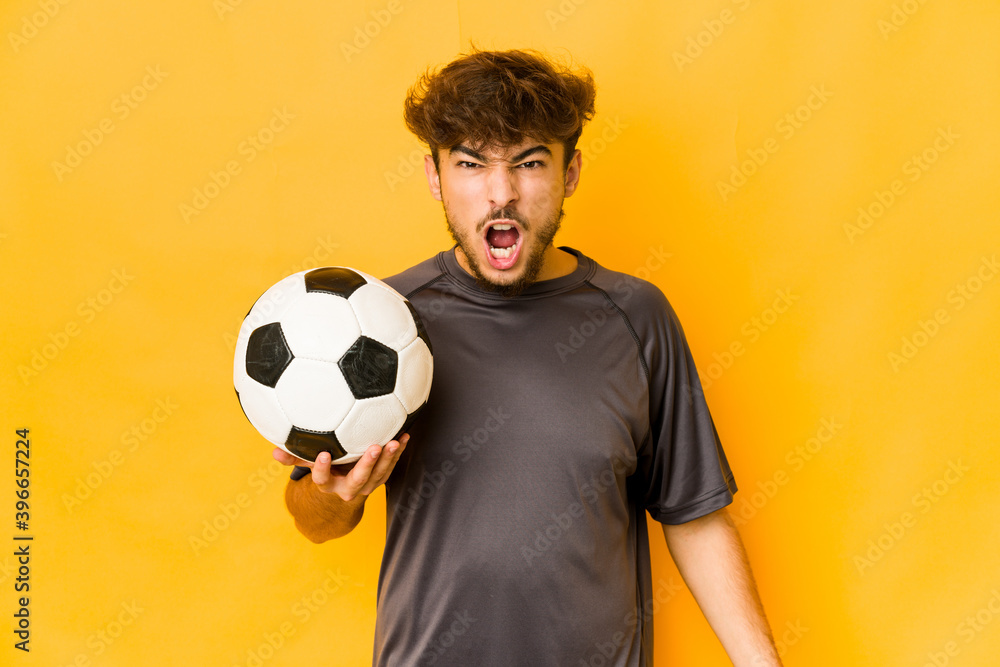 Young soccer player indian man screaming very angry and aggressive. Young soccer player indian man screaming very angry and aggressive.