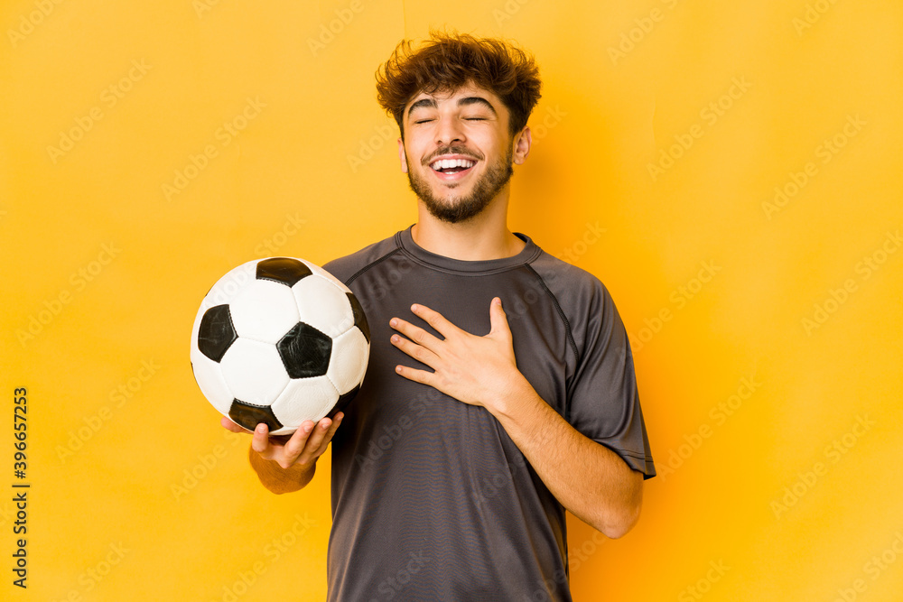 Young soccer player indian man laughs out loudly keeping hand on chest. Young soccer player indian man laughs out loudly keeping hand on chest.