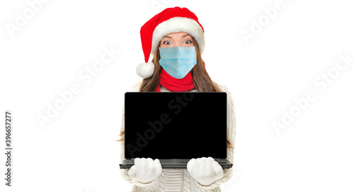 Christmas social distancing concept. Santa Asian girl wearing surgical mask doing virtual remote Xmas party online on black screen laptop computer cutout. Banner on white background.