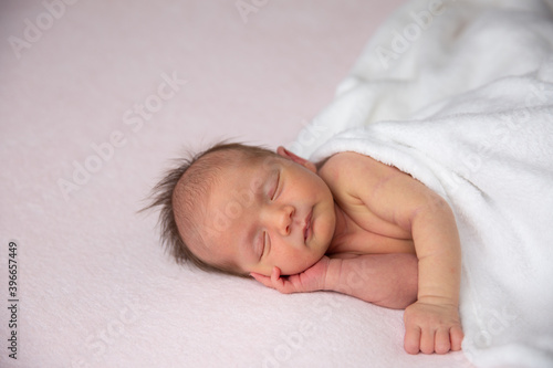 A cute little newborn baby is sleeping on a blanket.