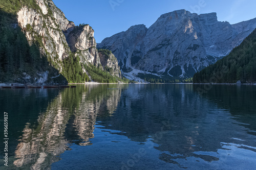 Reflections of Croda del Becco peak on the Braies lake towards sunset with boats moored, South Tyrol, Italy. Concept: relaxation in nature, famous natural places, film sets