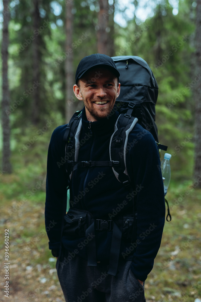Smiling man with rucksack standing in forest Smiling man with rucksack standing in forest