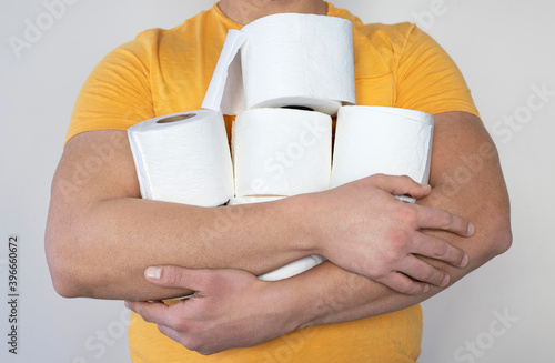 People are stocking up toilet paper for home quarantine from coronavirus. Man holds many rolls of toilet pape