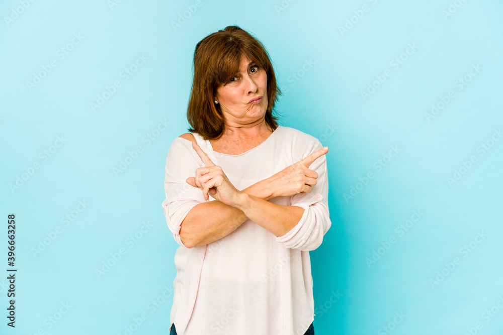 Fototapeta premium Senior caucasian woman isolated points sideways, is trying to choose between two options.
