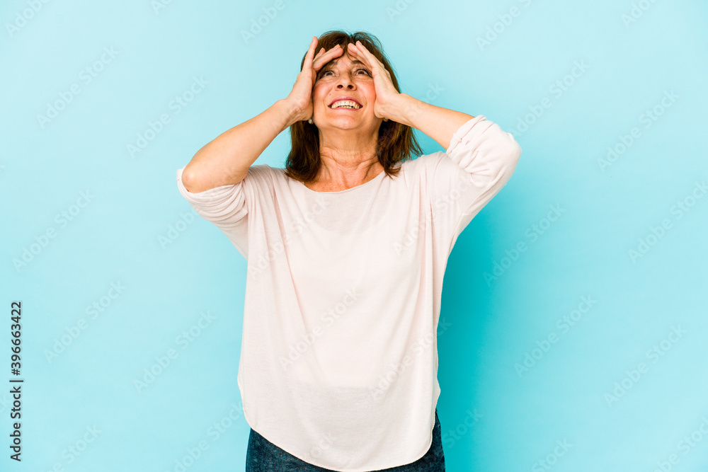 Senior caucasian woman isolated laughs joyfully keeping hands on head. Happiness concept.