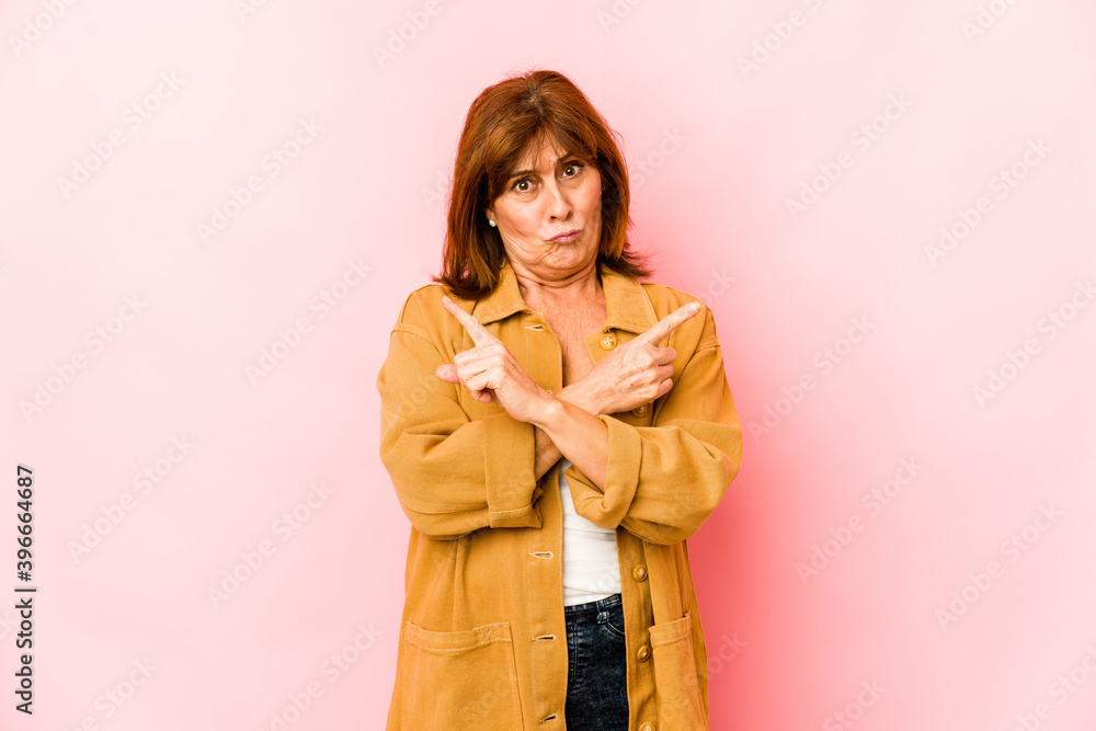Senior caucasian woman isolated points sideways, is trying to choose between two options. Senior caucasian woman isolated points sideways, is trying to choose between two options.
