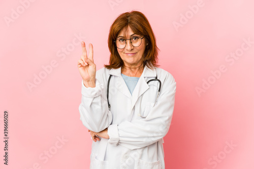 Middle age caucasian doctor woman isolated showing number two with fingers.
