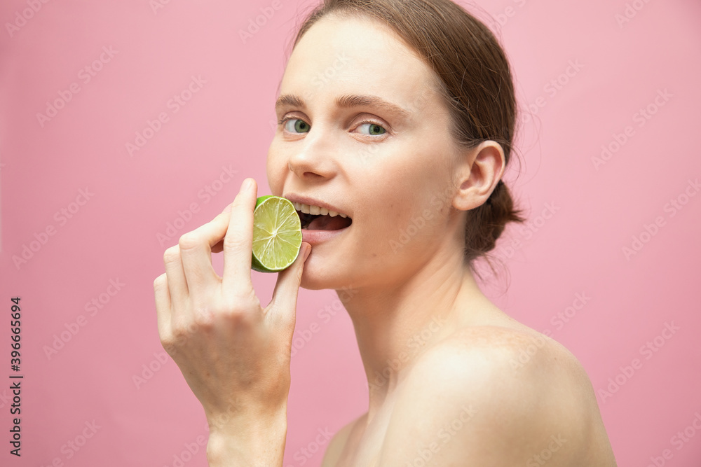 Beautiful sensual topless brunette woman standing isolated over pink background and eat lime Beautiful sensual topless brunette woman standing isolated over pink background and eat lime