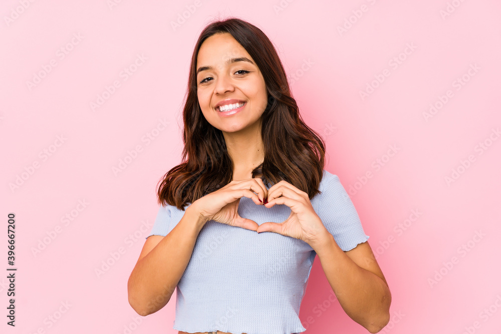 Young mixed race hispanic woman isolated smiling and showing a heart shape with hands. Young mixed race hispanic woman isolated smiling and showing a heart shape with hands.
