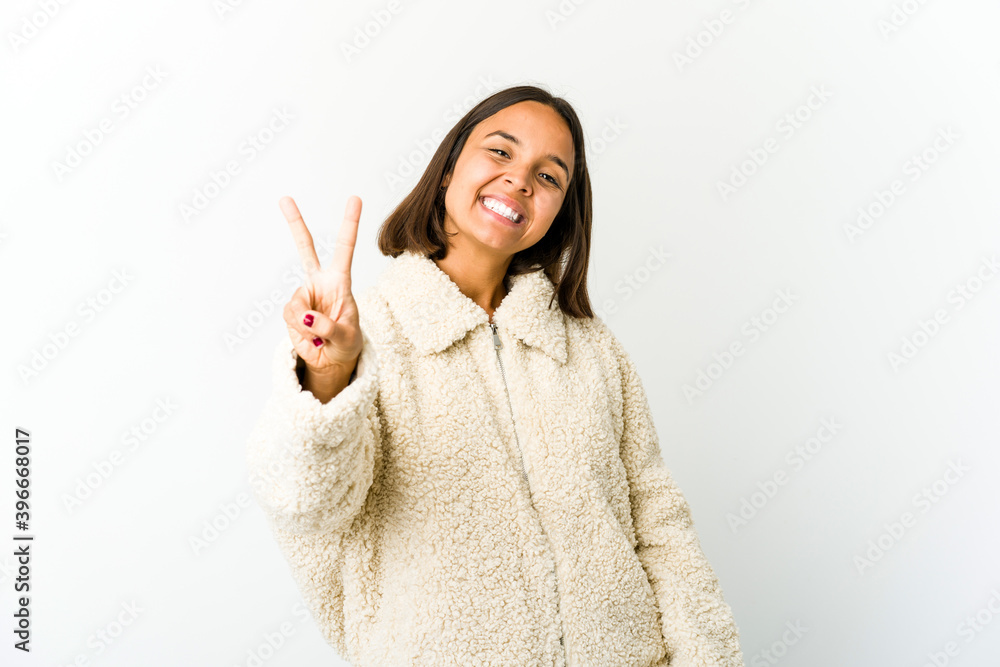 Young mixed race woman joyful and carefree showing a peace symbol with fingers. Young mixed race woman joyful and carefree showing a peace symbol with fingers.
