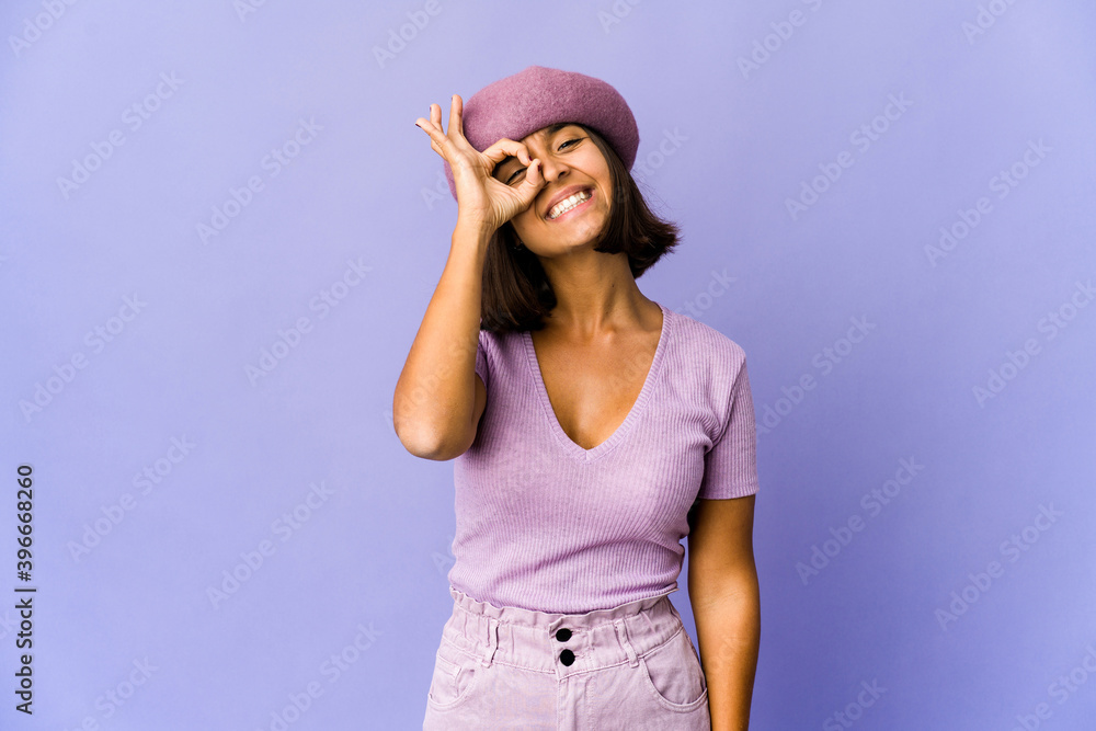 Young mixed race woman excited keeping ok gesture on eye. Young mixed race woman excited keeping ok gesture on eye.