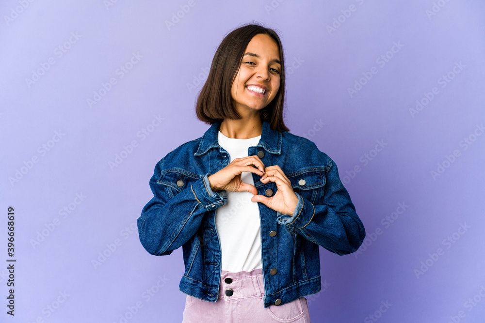 Young mixed race woman smiling and showing a heart shape with hands. Young mixed race woman smiling and showing a heart shape with hands.
