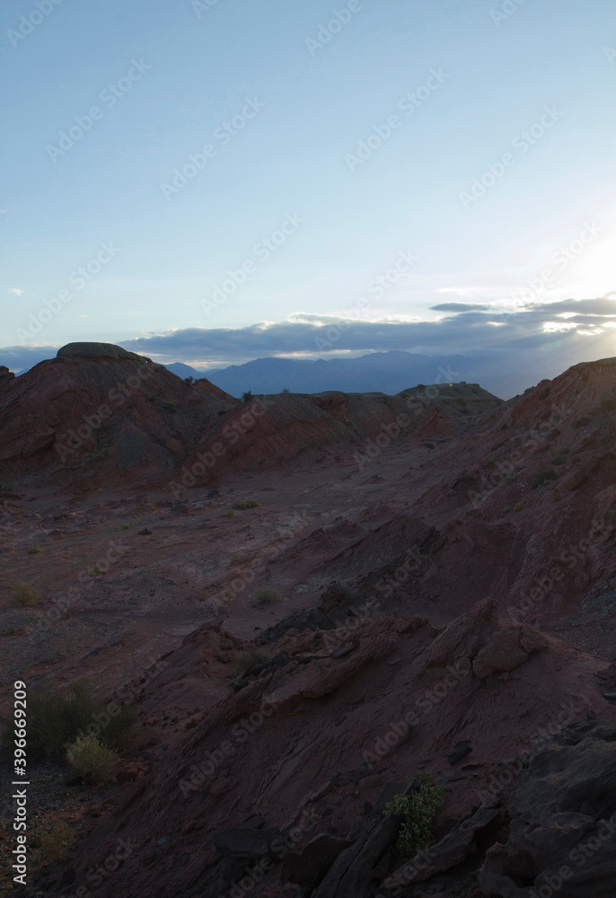 The red canyon and valley at sunset. Panorama view of the arid desert, sandstone formations, and rocky mountains in Talampaya national park in La Rioja, Argentina.