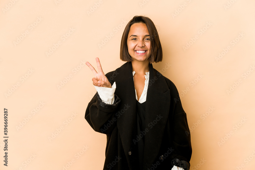 Young hispanic woman isolated showing victory sign and smiling broadly. Young hispanic woman isolated showing victory sign and smiling broadly.