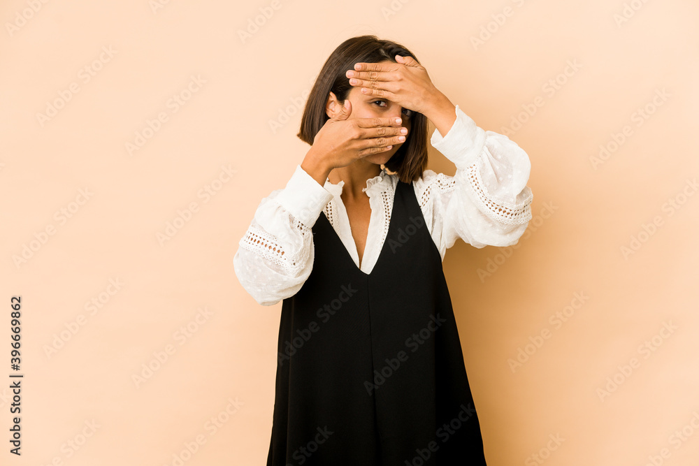 Young hispanic woman isolated blink at the camera through fingers, embarrassed covering face. Young hispanic woman isolated blink at the camera through fingers, embarrassed covering face.