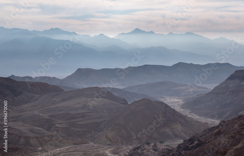 Panoramic view of the mountains chains at the sunrise in Eilat mountains, Southern Israel. Jordanian Edom mountains in the background. White clouds on the the blue sky.