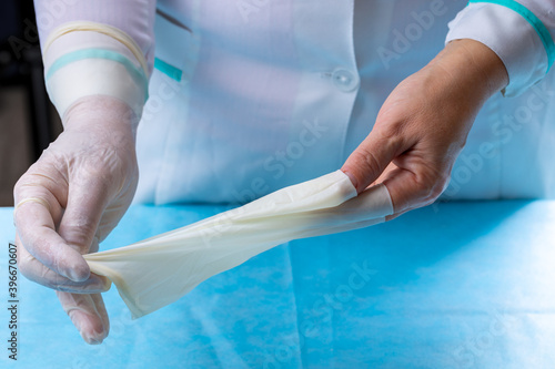 medical worker person putting off used surgical gloves after medical procedure. surgery latex gloves close up. protective uniform for nurse