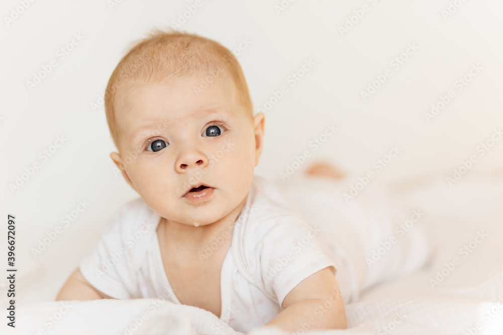 Portrait of adorable baby girl laying on comfortable bed at home, beautiful cute toddler look at the camera with big interest, childhood and childcare concept
