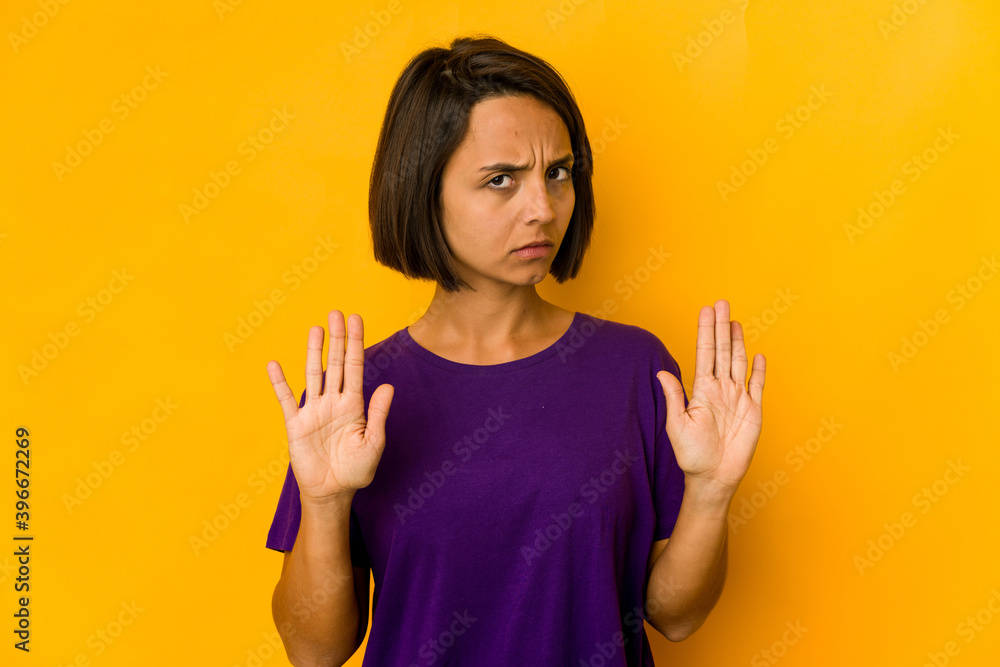 Young hispanic woman isolated on yellow standing with outstretched hand showing stop sign, preventing you. Young hispanic woman isolated on yellow standing with outstretched hand showing stop sign, preventing you.