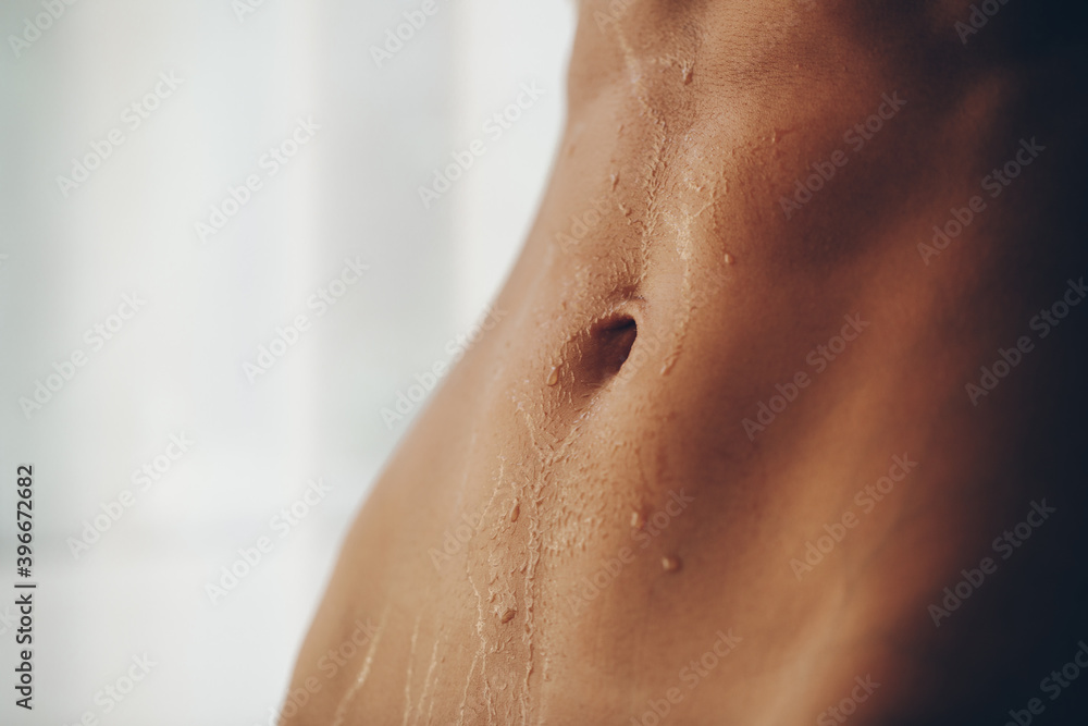 Fototapeta premium Close up of fit woman torso with sweat on skin after workout. Female with perfect abdomen muscles 