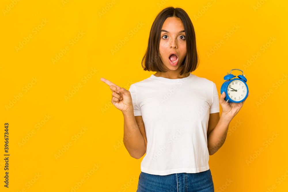 Young hispanic woman holding a megaphone pointing to the side Young hispanic woman holding a megaphone pointing to the side