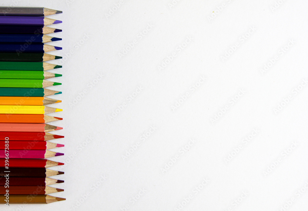 colored pencils lie in a row on a white background colored pencils lie in a row on a white background