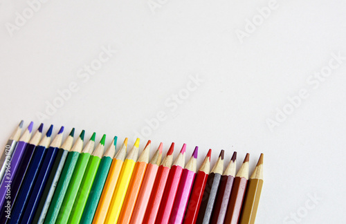 colored pencils lie in a row on a white background