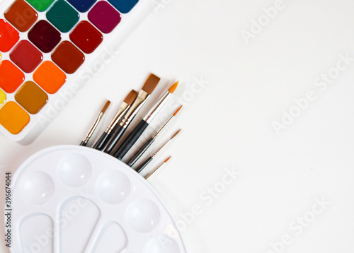 watercolor paints palette and brushes on a white background