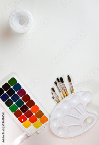 watercolor paints palette and brushes with non-spill on a white background