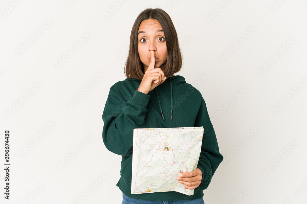 Young hispanic traveler woman holding a map keeping a secret or asking for silence. Young hispanic traveler woman holding a map keeping a secret or asking for silence.