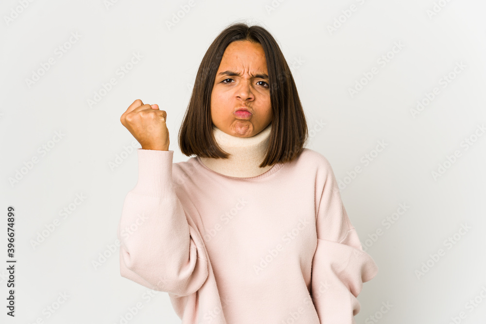 Young hispanic woman wearing a collar showing fist to camera, aggressive facial expression. Young hispanic woman wearing a collar showing fist to camera, aggressive facial expression.