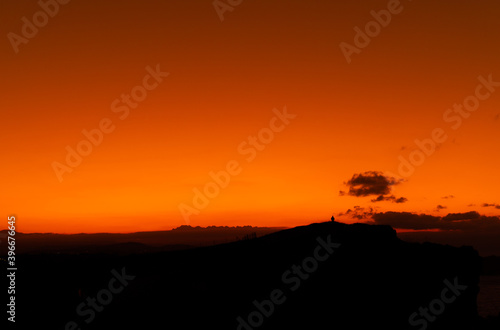 orange sunset with mountain silhouette and a person