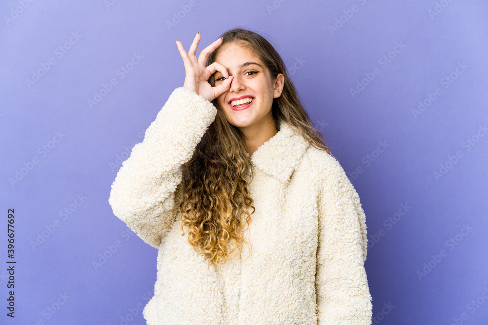 Young caucasian cute woman excited keeping ok gesture on eye. Young caucasian cute woman excited keeping ok gesture on eye.