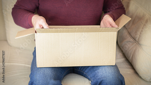 A man unpacks a parcel from a cardboard box